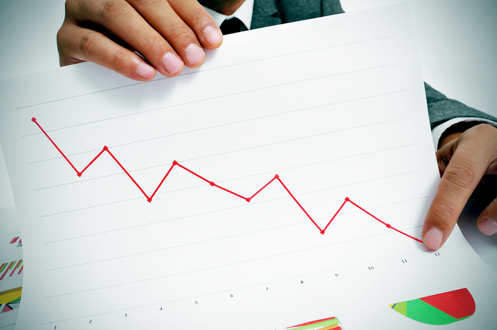 Man pointing to chart showing losses with pencil